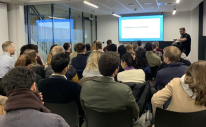 A room full of audience listening to the speaker presenting