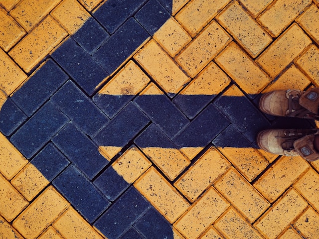 Arrow painted on the pavement and a pair of shoes of a person at the start of the arrow